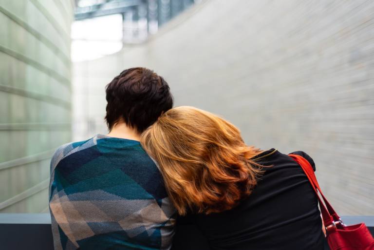 Two individuals sitting closely in a supportive embrace.